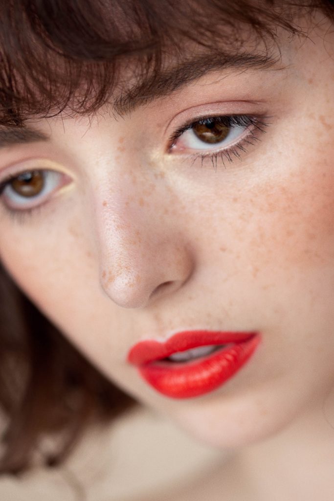 Model with perfect freckled skin and red lips, shot by Mariana Quevedo